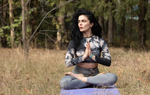 Foto frau sitzt in der lotusposition im freien in naturmeditation und yoga-konzept