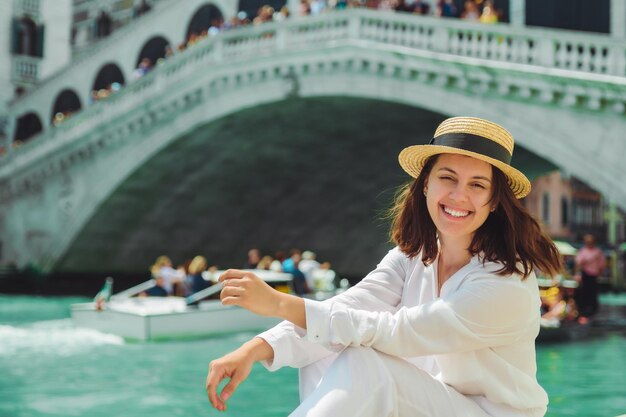 Frau sitzt in der Nähe der Rialtobrücke in Venedig Italien und blickt auf den Canal Grande mit Gondeln Sommerzeit Kopierraum