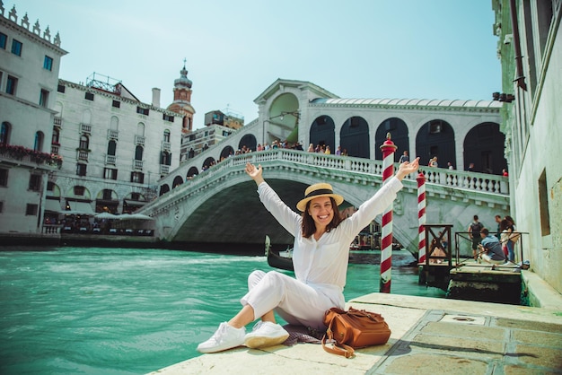 Frau sitzt in der Nähe der Rialtobrücke in Venedig Italien und blickt auf den Canal Grande mit Gondeln Sommerzeit Kopierraum