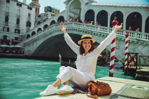 Frau sitzt in der Nähe der Rialtobrücke in Venedig Italien und blickt auf den Canal Grande mit Gondeln Sommerzeit Kopierraum