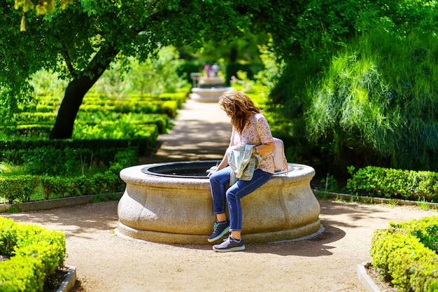 Frau sitzt in einem kleinen Brunnen mit frischem Wasser in der Mitte des Gartens