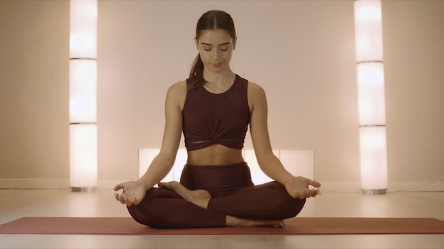 Frau sitzt in Lotus-Pose auf Matte drinnen Trainer praktiziert Yoga im Studio