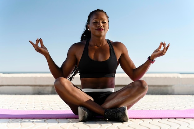 Frau sitzt in Lotus-Pose und genießt Freizeit für Yoga-Praxis am Meeresstrand