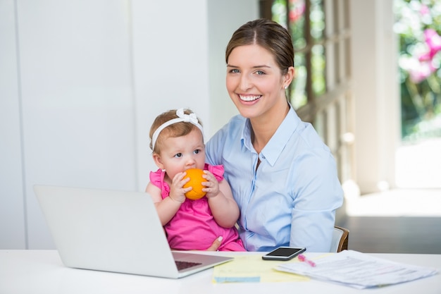 Frau sitzt mit Baby am Tisch