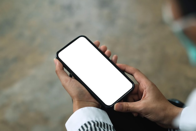 Frau sitzt mit einem leeren weißen Smartphone-Bildschirm im Büro Mock-up für Textnachrichten oder Informationen