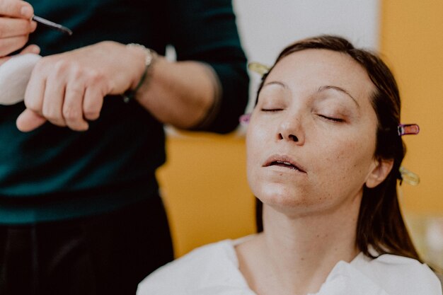 Foto frau sitzt mit geschlossenen augen von einem make-up-künstler