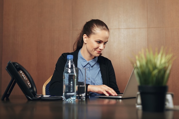 Frau sitzt mit Laptop im Büro am Tisch