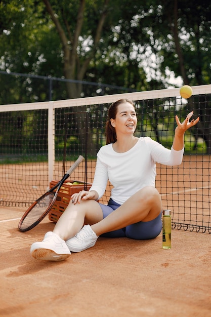 Frau sitzt mit Netz auf Tennisplatz. Ausruhen nach dem Spiel