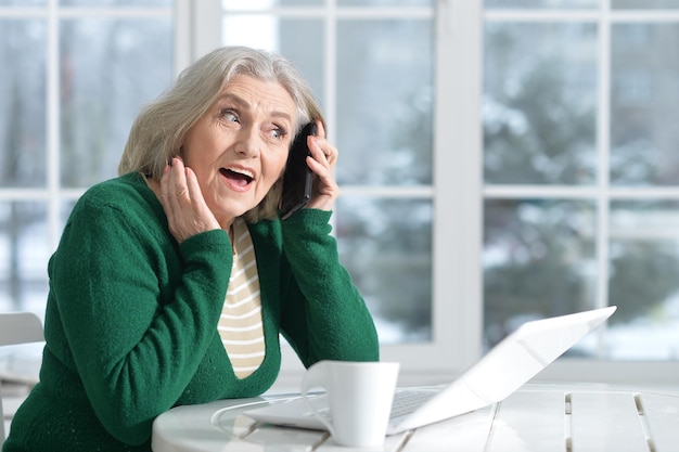 Frau sitzt mit Telefon am Tisch