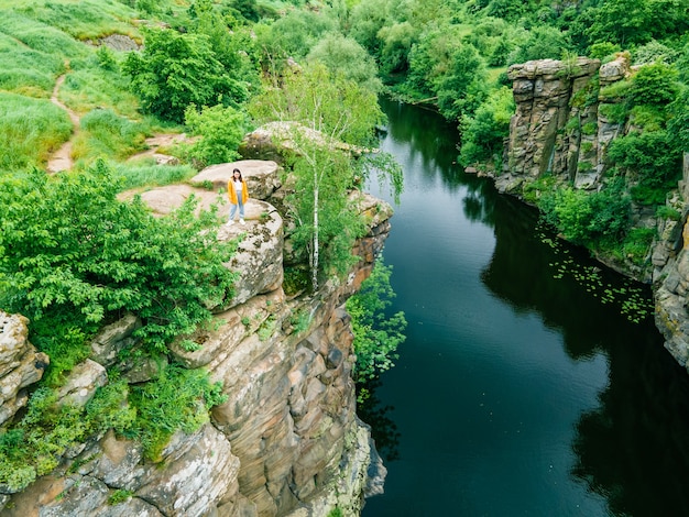 Frau sitzt oben und genießt den Blick auf den Canyon-Flusswald