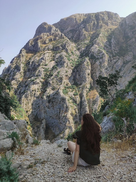 Frau sitzt und betrachtet Berge von oben in Kotor Montenegro