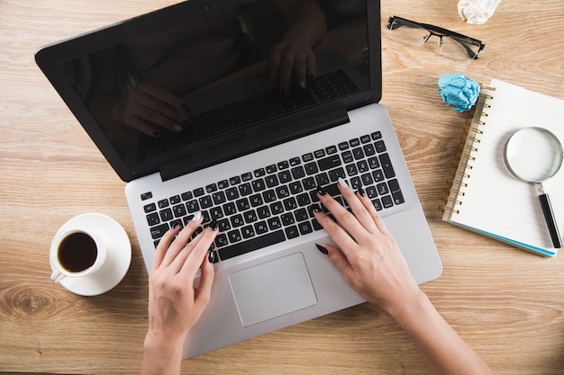 Frau sitzt vor Arbeitstisch mit Laptop