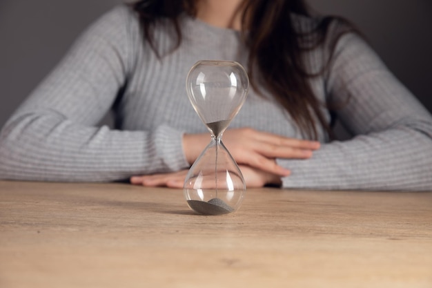 Frau sitzt vor einer Sanduhr