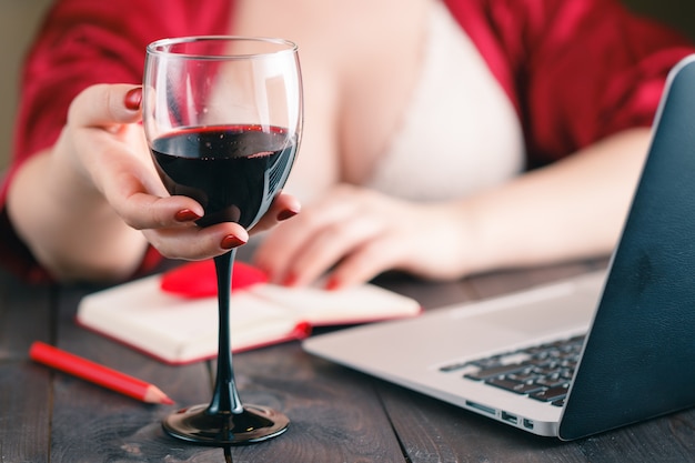 Frau sitzt zu Hause Tisch mit einem Glas Rotwein