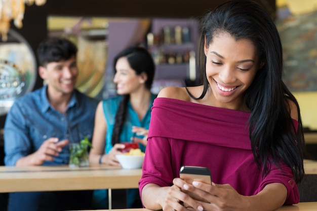 Frau SMS am Telefon an der Kaffeebar