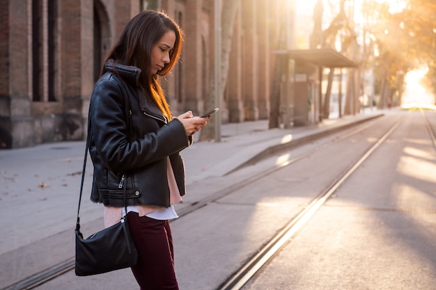 Frau SMS am Telefon beim Überqueren der Straße