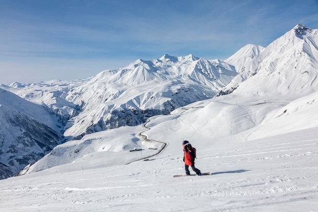Frau Snowboarder Freerider fährt von der Spitze des Grats in einem großen Gebirge herunter