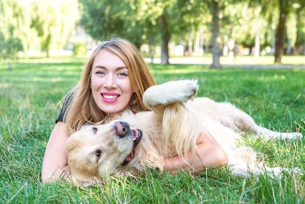 Frau spielt draußen mit ihrem Hund Retriever.