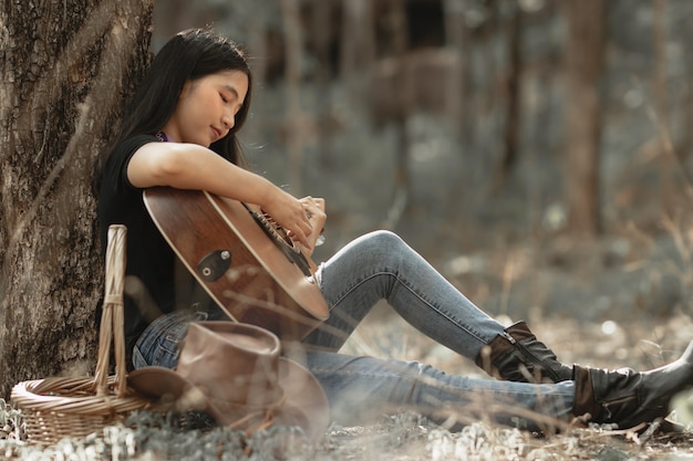Frau spielt Gitarre mit glücklich im Wald.