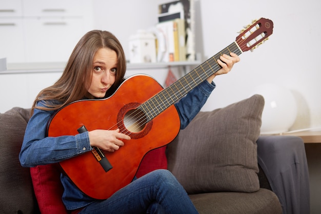 Frau spielt Gitarre zu Hause