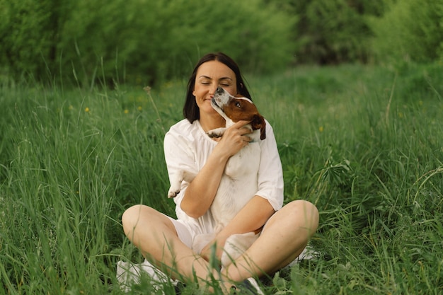 Frau spielt Jack Russell Terrier Hund auf der Wiese. Frau umarmt Jack Russell Terrier Hund in der Natur.