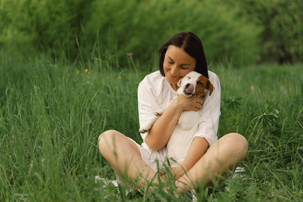 Frau spielt Jack Russell Terrier Hund auf der Wiese. Frau umarmt Jack Russell Terrier Hund in der Natur.