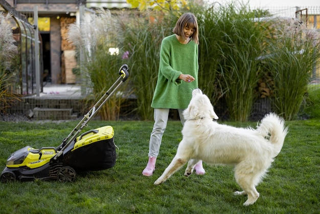 Frau spielt mit ihrem Hund im Hinterhof bei der Gartenarbeit