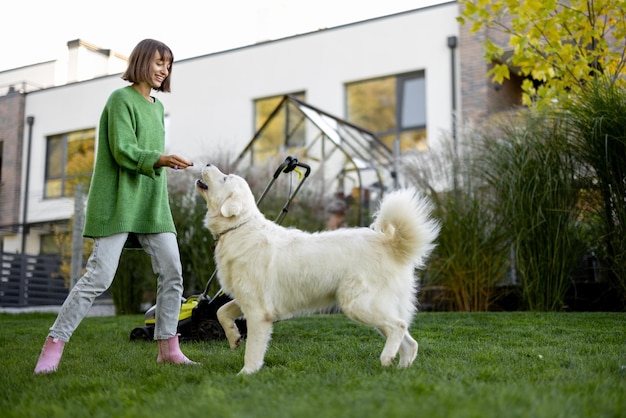 Frau spielt mit ihrem Hund im Hinterhof bei der Gartenarbeit