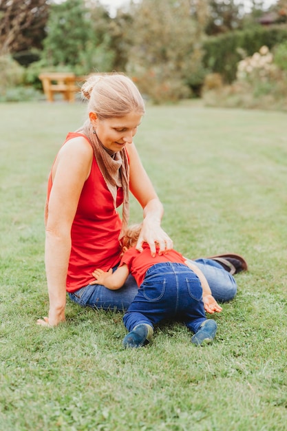 Foto frau spielt mit ihrer tochter, während sie auf dem feld sitzt