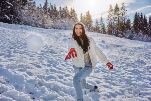 Frau spielt Winterspiel Schneeball im Bergwald im Freien zu werfen