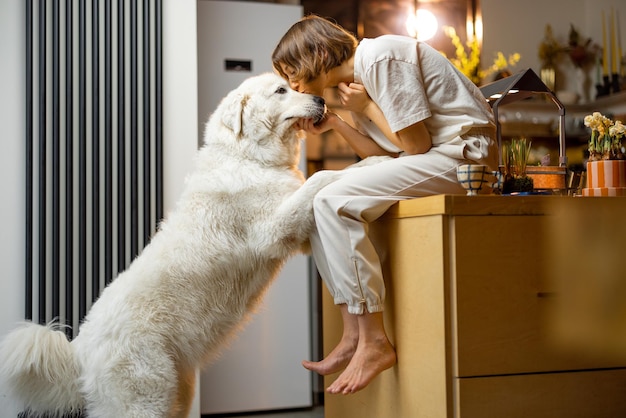 Frau spielt zu Hause mit ihrem Hund in der Küche