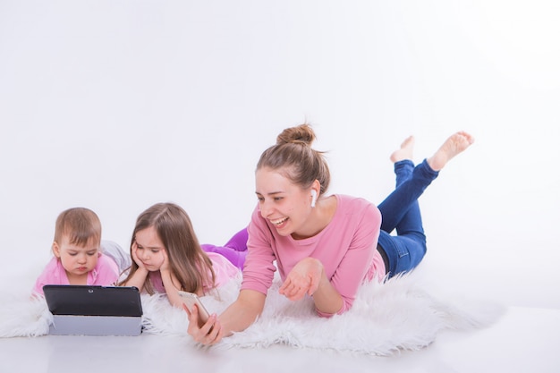 Frau spricht am Telefon durch Headset und Kinder sehen Karikatur auf Tablette