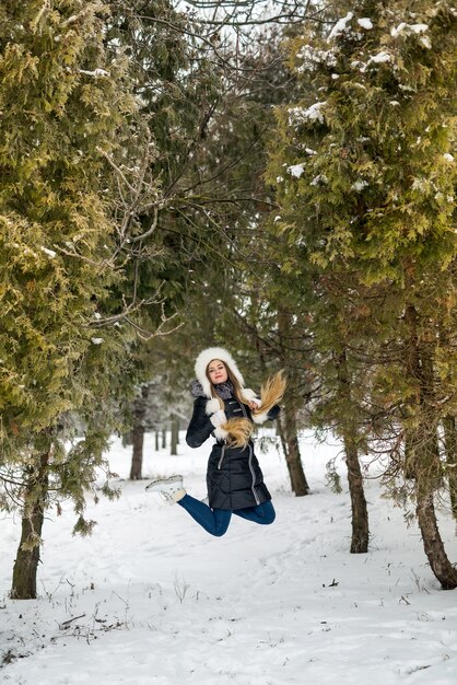 Frau springt zwischen Bäumen im Winterpark