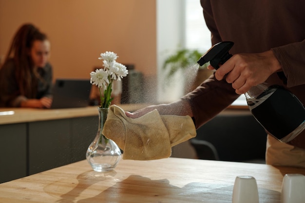 Frau sprüht Sanitizer auf Duster