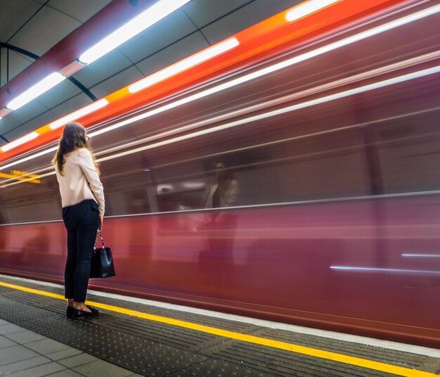 Frau steht am Bahnsteig des Bahnhofs neben dem Zug