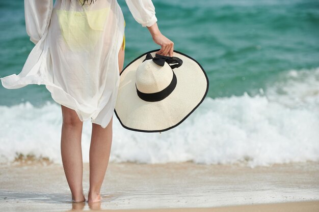 Frau steht am Sandstrand