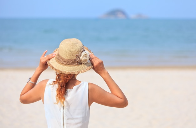 Frau steht am Strand und schaut aufs Meer