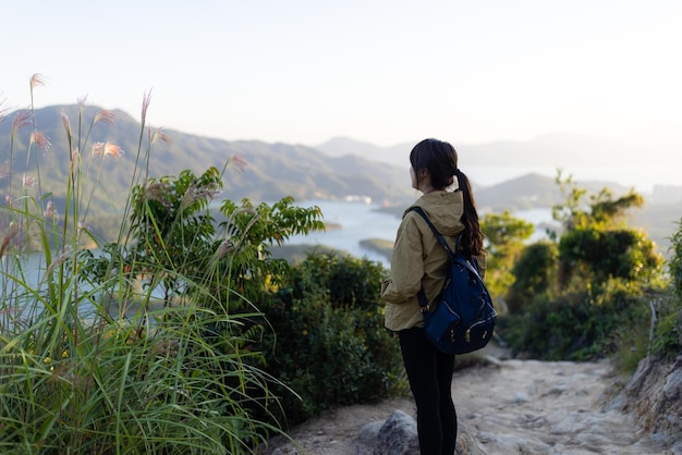 Frau steht auf dem Berg und schaut sich die Landschaft an