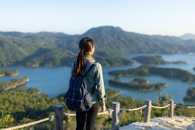 Frau steht auf dem Berg und schaut sich die Landschaft an