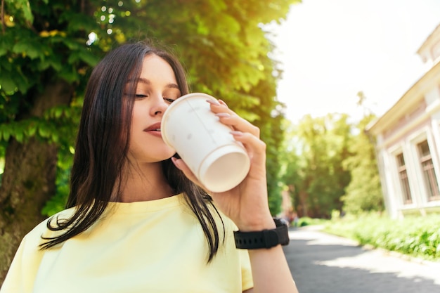 Frau steht auf der Straße und trinkt Kaffee