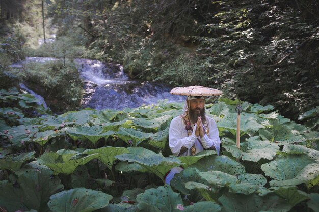 Foto frau steht auf einem felsen gegen einen wasserfall