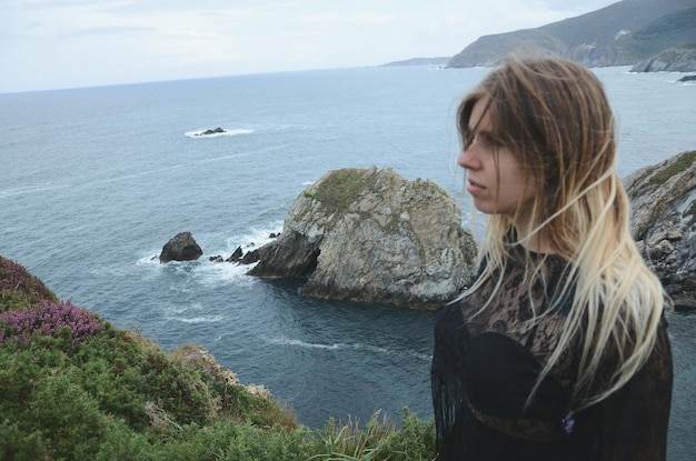 Foto frau steht auf einer klippe am meer