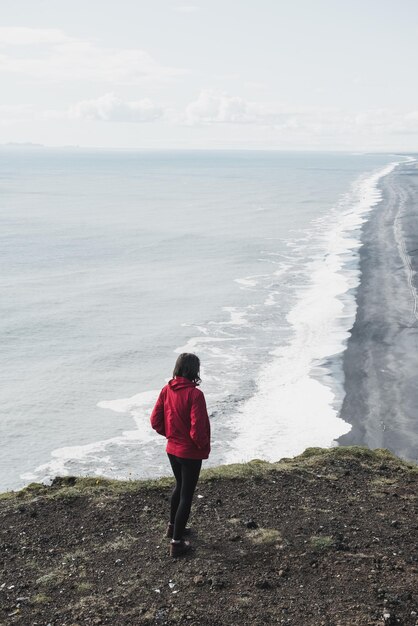 Foto frau steht auf einer klippe in island