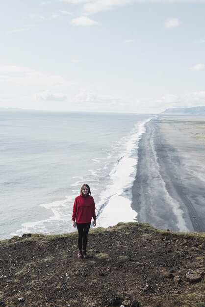 Frau steht auf einer Klippe in Island