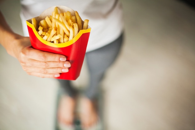 Foto frau steht auf waage und hält kartoffelchips