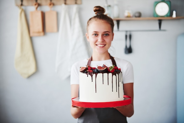 Frau steht drinnen in der Küche mit hausgemachtem Kuchen.