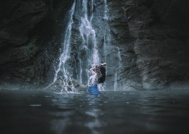 Foto frau steht im fluss gegen eine felsformation