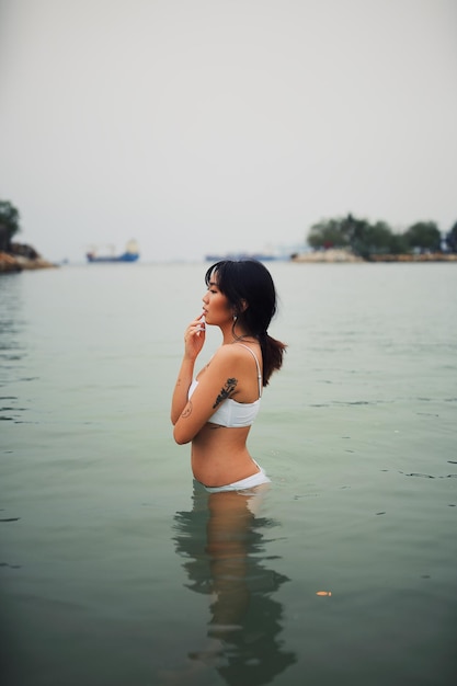 Frau steht im Meer gegen den Himmel
