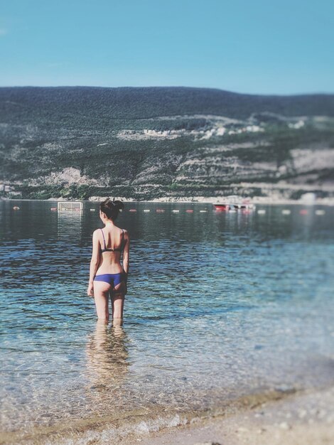 Foto frau steht im meer vor klarem himmel