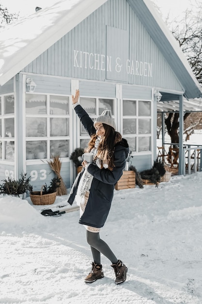 Frau steht im Winter am Haus und genießt die Sonne